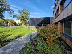 Škola v Českobrodské ulici od ECOTEN: Pro povrchovou úpravu ENVILOP autoři rekonstrukce zvolili vláknocementové fasádní desky Swisspearl Patina Original (dříve Cembrit) a dřevěný obklad, konkrétně rombusové tyče ze sibiřského modřínu bez povrchové úpravy