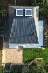 Jedna nová místnost je hned pod vysokou střechou, které po svém obvodu nemá žádná okna, vypadá tedy čistě jako střecha bez obytného podkroví. (Chata v Posázaví, Atelier Hajný)