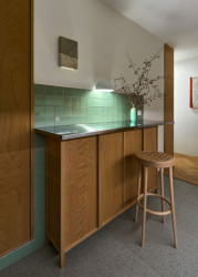Na uvolněné straně kuchyně vznikl zvýšený barový pult, u kterého je možné sedět ve dvou až třech lidech. (Rekonstrukce bytu ve Vršovicích, Amulet architekti)