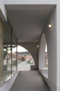 Podloubím prochází veřejný chodník, který v případě nepřízně počasí poskytuje úkryt jak před sluncem, tak i před deštěm. (Sokolovna ve Veverských Knínicích, studio New Work)