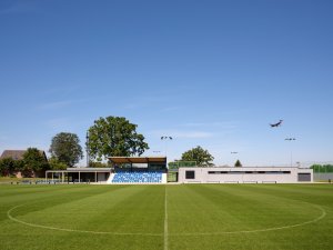 Objekt zázemí zahrnuje šatny, klubovnu, občerstvení, prostor pro regeneraci a tribunu s kapacitou 120 diváků. (Sportovní areál SK Planá, PROAM ARCHITEKTI)