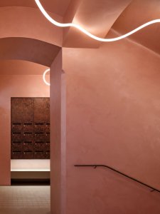 Dostaly růžovou barvu, liniové světlo, za vstupem jsou dýhované schránky. (Rekonstrukce pavlačového domu v Praze-Nuslích, Plus One Architects) 