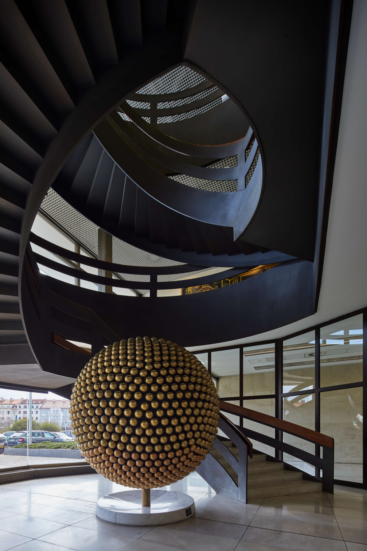 Procházka je podepsaný také pod plastikou Slunce, kterou najdeme pod dominantním ocelovým schodištěm.