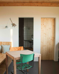 Obývací pokoj dále pokračuje do dvou místností. Nalevo je koupelna. 