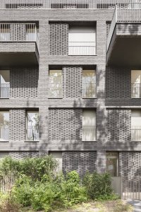 Studio AVENIER CORNEJO architectes navrhlo na břehu kanálu na předměstí Paříže obytný soubor třech domů s různým odstínem lícových cihel