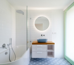 V bílé koupelně je překvapivým prvkem obložení podlahy. Má takový „portugalský“ nádech. 