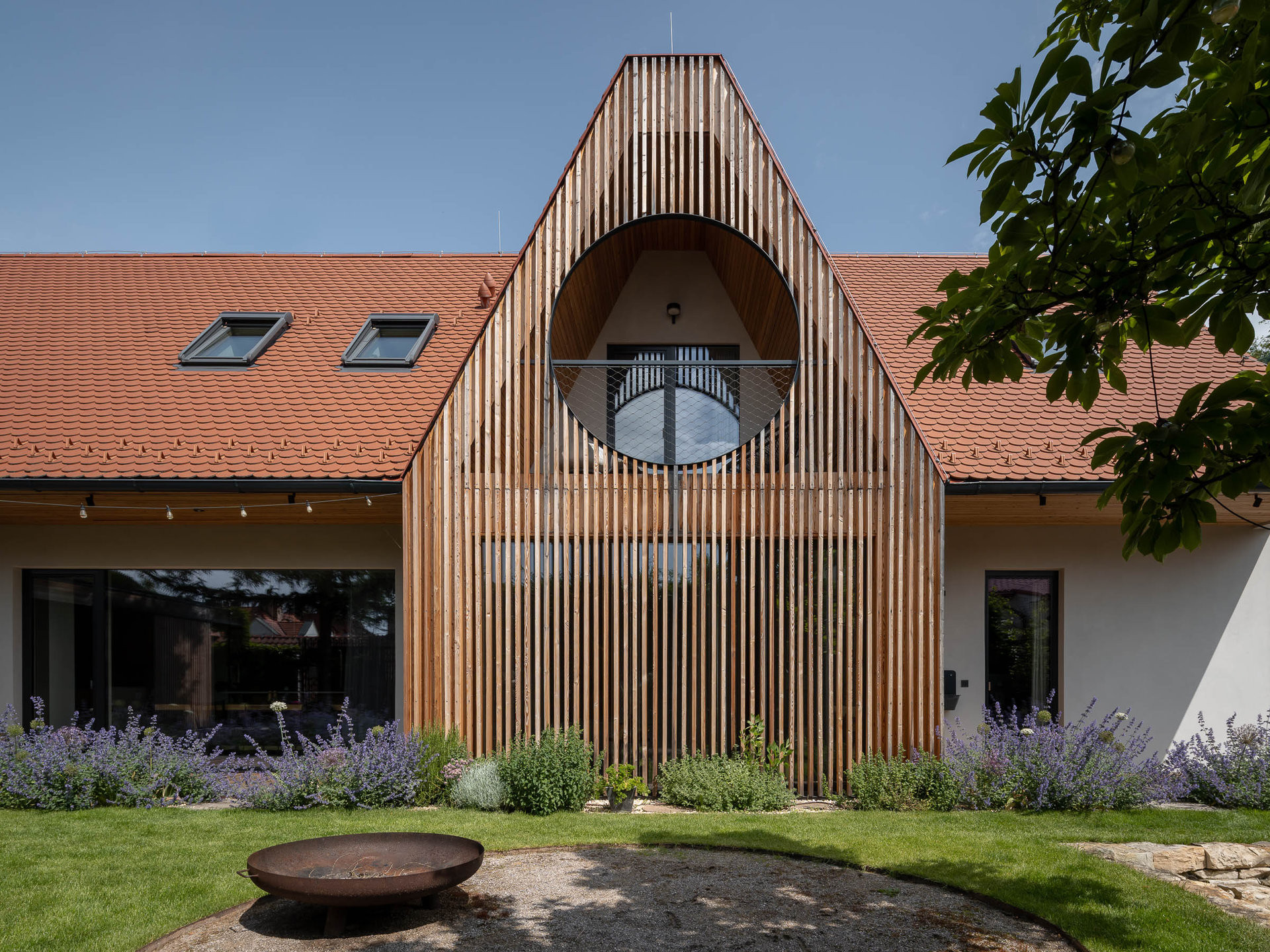 Dům ve Střešovicích má tradiční proporce i současné prvky, třeba kulaté okno v podkroví. (Rodinný dům v Břevnově; OTA atelier)