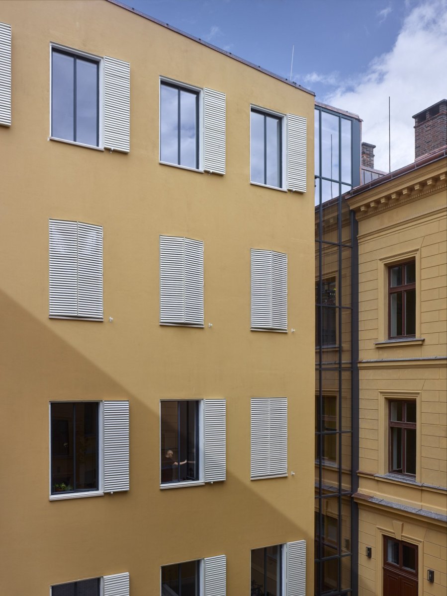 Od původní budovy je dostavba oddělená prosklenou výtahovou šachtou