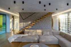 Obývacímu pokoji dominuje masivní dřevěné schodiště levitující v prostoru. (Vila v Trněném Újezdě, de.fakto)