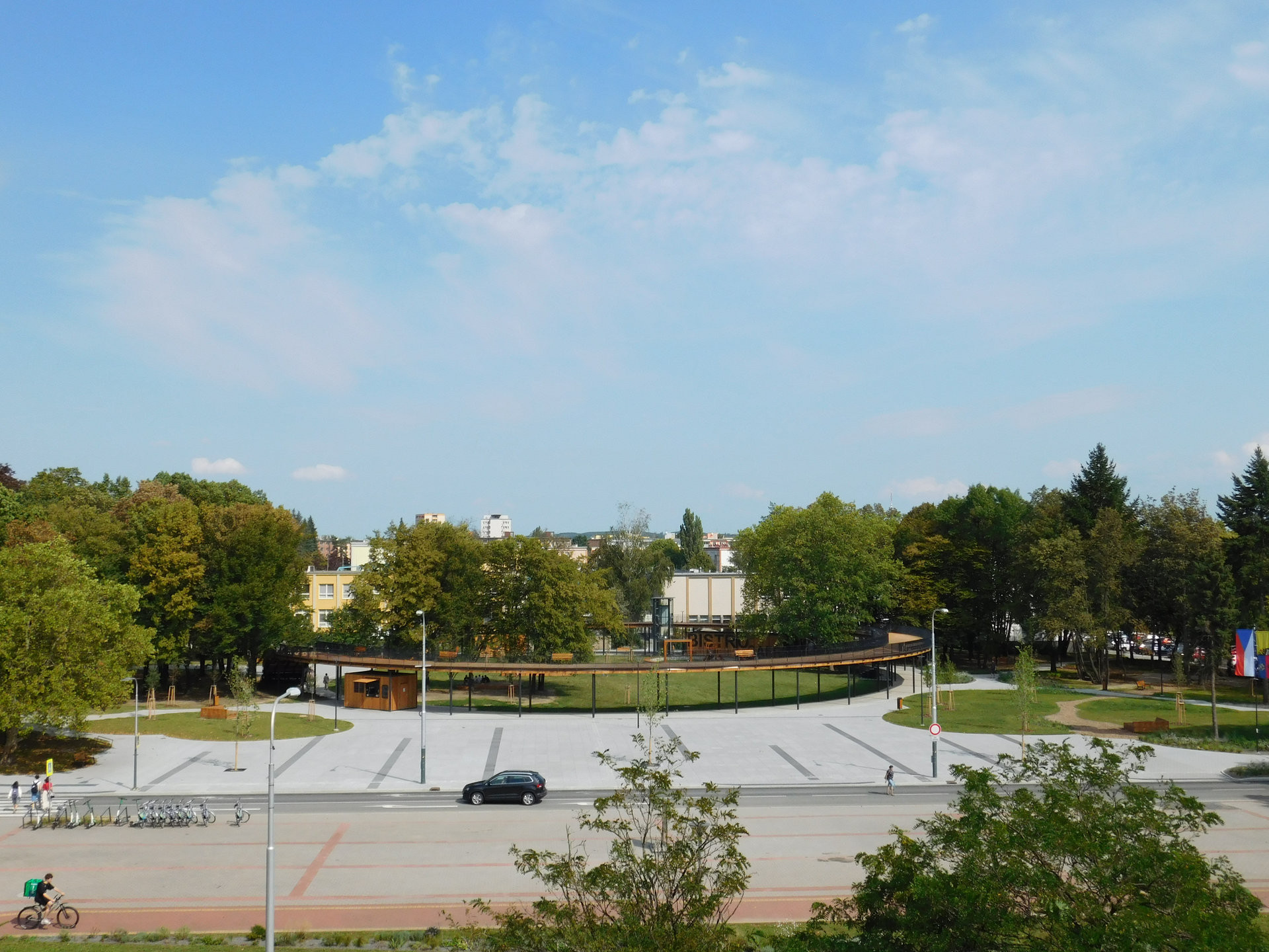 Před prstencem je plocha z velkoformátové dlažby, která opět slouží ke konání akcí, naopak parkování podél cesty bylo zrušeno.