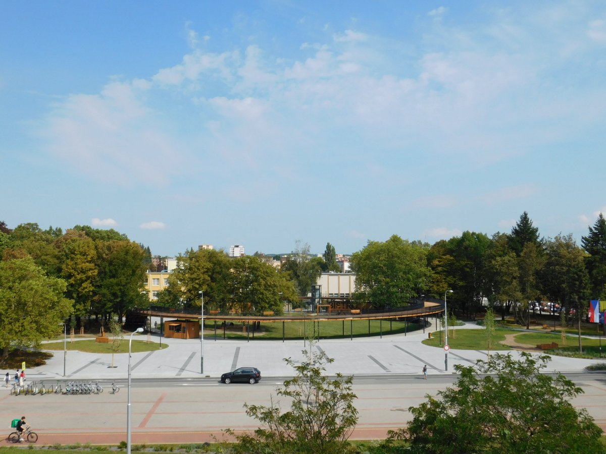 Před prstencem je plocha z velkoformátové dlažby, která opět slouží ke konání akcí, naopak parkování podél cesty bylo zrušeno.