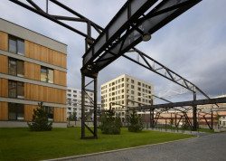 Kovové konstrukce se tyčí nad hlavami procházejících (Rezidenční bydlení vzniklo z holešovického brownfieldu; A69 architekti)