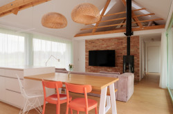 Minimalistickou atmosféru interiéru záměrně narušuje barevně zvolený nábytek a kontrastní zelené rámy oken.