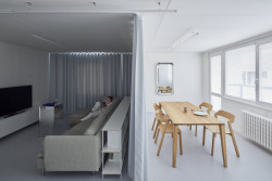 Obývací pokoj rozdělený závěsem na dvě oddělené zóny.