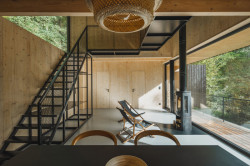 Velkorysý hlavní prostor je možný díky skromným pokojům v patře.  (Chata u Sázavy mezi skálou a řekou; Mimosa Architekti)