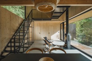Velkorysý hlavní prostor je možný díky skromným pokojům v patře.  (Chata u Sázavy mezi skálou a řekou; Mimosa Architekti)