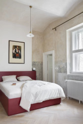 Postel navrhly designérky z červeně natřené dřevěné dýhy. Barva i materiál evokuje předválečnou modernu. (Apartmán v Laichterově domě, Other Projects Studio)