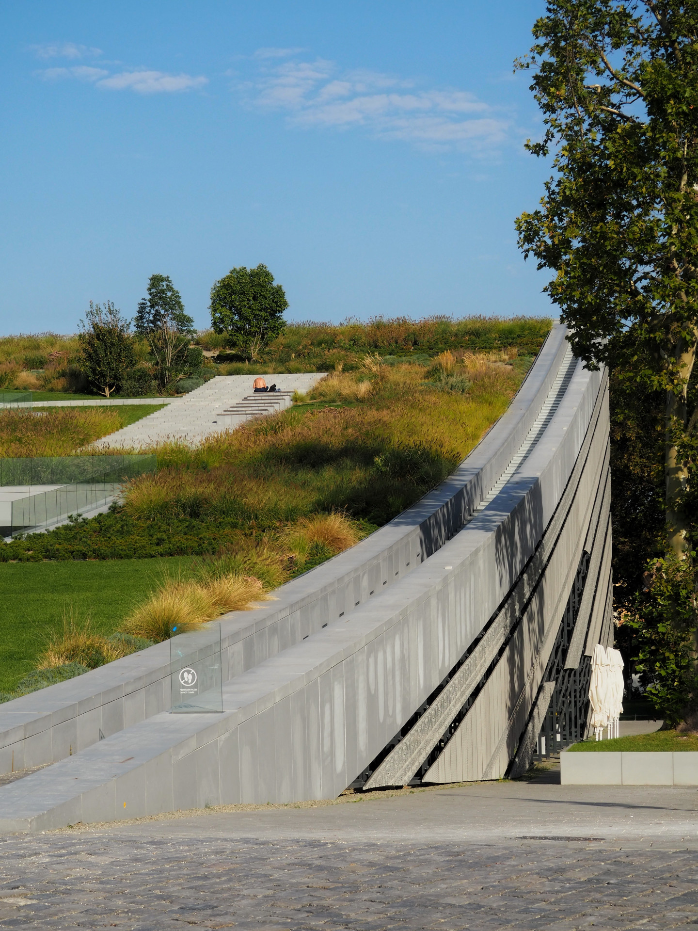 Budova za 120 milonů eur je součástí většího plánu. V okolí vyrostl Dům hudby od japonského architekta Sou Fujimota, chystá se Národní galerie od studia SANAA a další obří investice – vše v režii krajně pravicové vlády Viktora Orbána.