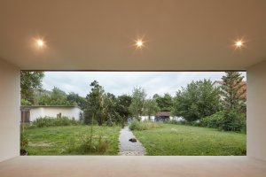 Betonové „nohy“ zajišťují nejen ochranu domu před povodněmi, ale také vytváří výrazný architektonický prvek a krytý venkovní prostor mezi podstavami. (Rodinný dům v Řevnicích, 0,5 studio)