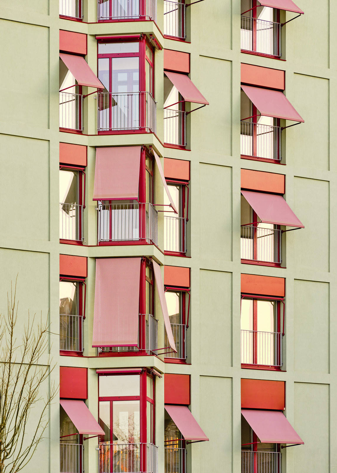 Pohled na fasádu domu, okna stíní markýzy (Bytový dům La Comunidad Habitacional v Barceloně; Cierto Estudio)