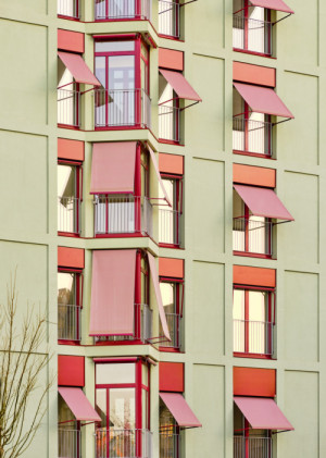 Pohled na fasádu domu, okna stíní markýzy (Bytový dům La Comunidad Habitacional v Barceloně; Cierto Estudio)