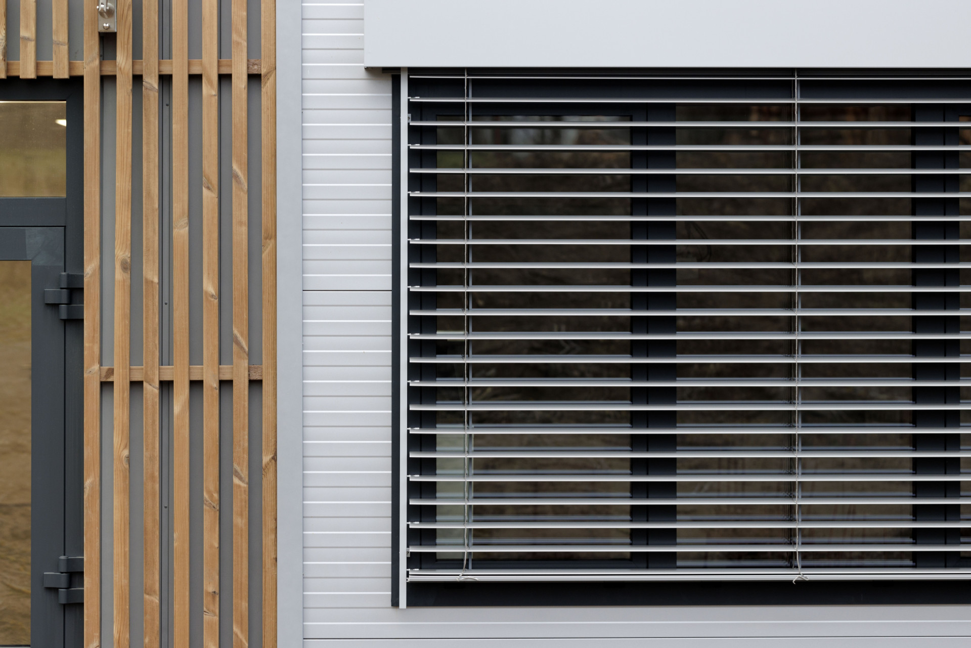 Moderní vzhled dodává stavbě použití elegantních šedých PUR panelů, velkých hliníkových oken a venkovních žaluzií. (ZŠ Drahanovice od společnosti KOMA)