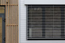 Moderní vzhled dodává stavbě použití elegantních šedých PUR panelů, velkých hliníkových oken a venkovních žaluzií. (ZŠ Drahanovice od společnosti KOMA)