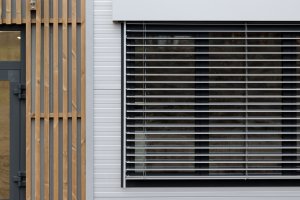 Moderní vzhled dodává stavbě použití elegantních šedých PUR panelů, velkých hliníkových oken a venkovních žaluzií. (ZŠ Drahanovice od společnosti KOMA)