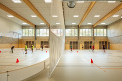 V tělocvičně dominují dřevěné prvky, pohledový beton a šedá podlaha s barevnými čárami pro různé sporty. (ZŠ bratří Fričů v Ondřejově; ATELIER 6)