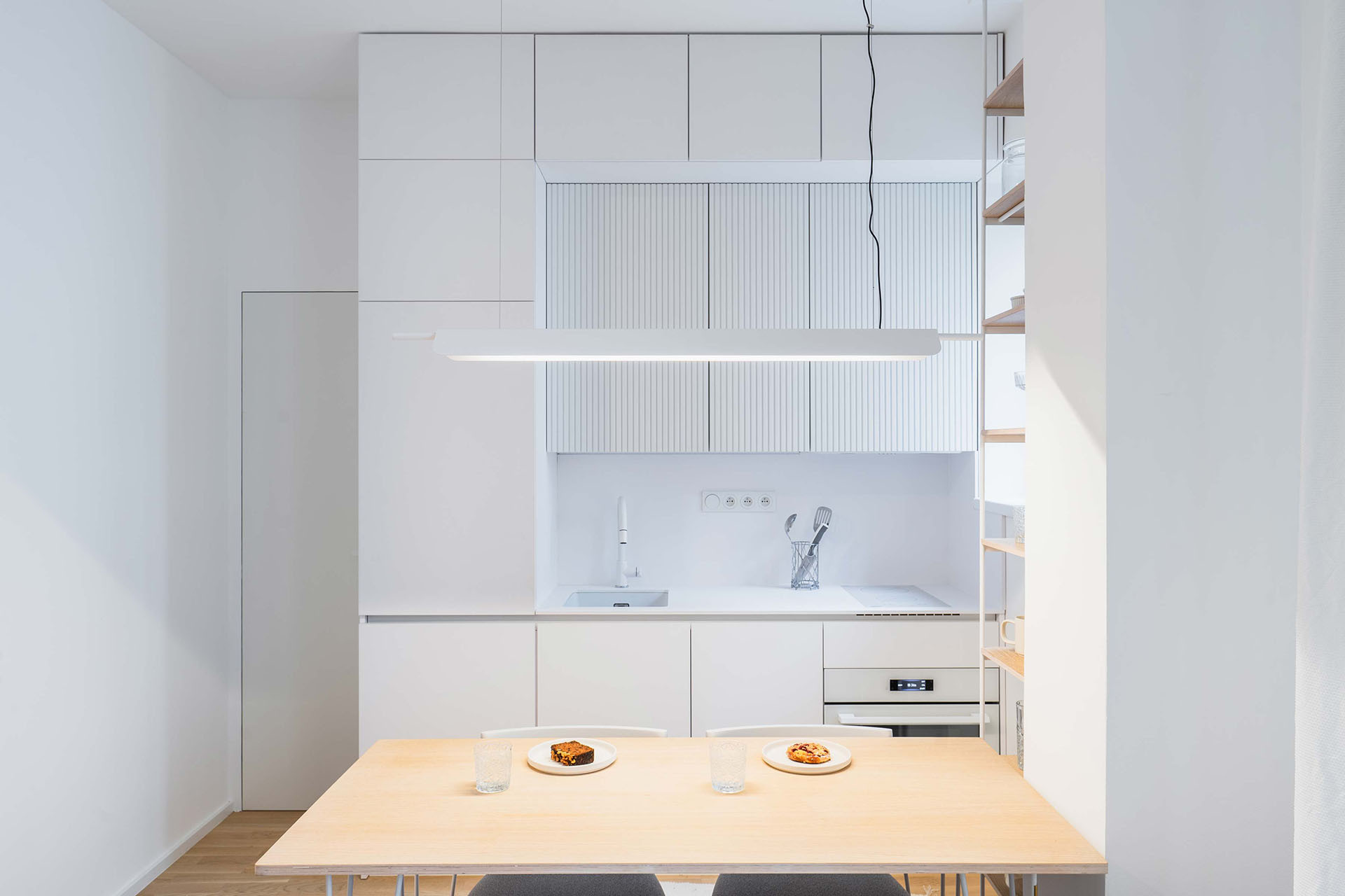 Kuchyně se otevírá do obývacího pokoje, původně byla schovaná v samostatné a malé místnosti. (Rekonstrukce bytu v Karlíně, Dominik Cvrček)