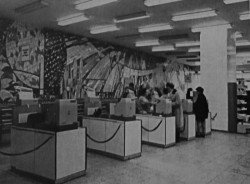 Pohled do interiéru. Na stěně za pokladnami je patrná rozsáhlá mozaika.