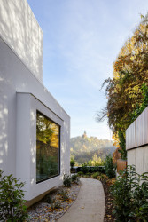 Zákoutí domu s průhledy do okolní krajiny. Za oknem je v interiéru umístěn čtecí koutek. (Block House v Šáreckém údolí v Praze; Studio MA)