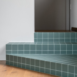 Tři schody obložené kachličkami propojují obývací pokoj s dalším rozmístěním. 