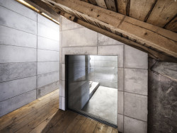 Skrze prosklené plochy betonového objektu lze nahlédnout na vrchní část cihelné klenby nebo na původní krov