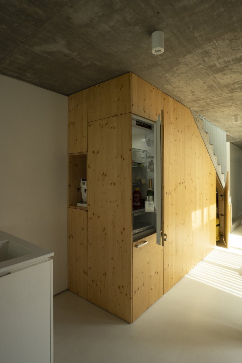 Prostor pod schodištěm je využit pro kuchyňské zázemí s ledničkou, kávovarem a spíží. (Úzký patrový dům v Žilině, architektonické studio treea - architekt Peter Kasman.)