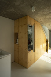 Prostor pod schodištěm je využit pro kuchyňské zázemí s ledničkou, kávovarem a spíží. (Úzký patrový dům v Žilině, architektonické studio treea - architekt Peter Kasman.)