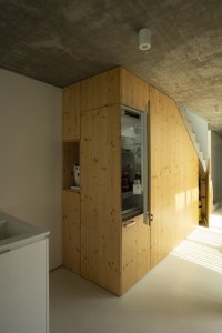 Prostor pod schodištěm je využit pro kuchyňské zázemí s ledničkou, kávovarem a spíží. (Úzký patrový dům v Žilině, architektonické studio treea - architekt Peter Kasman.)