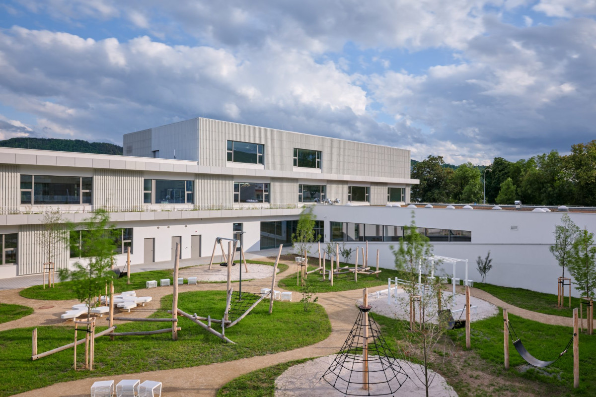 Architekti využili svažitý terén, a třípodlažní budovy tak působí dojmem dvoupodlažní stavby. (Nová škola Via v Berouně; OVA )