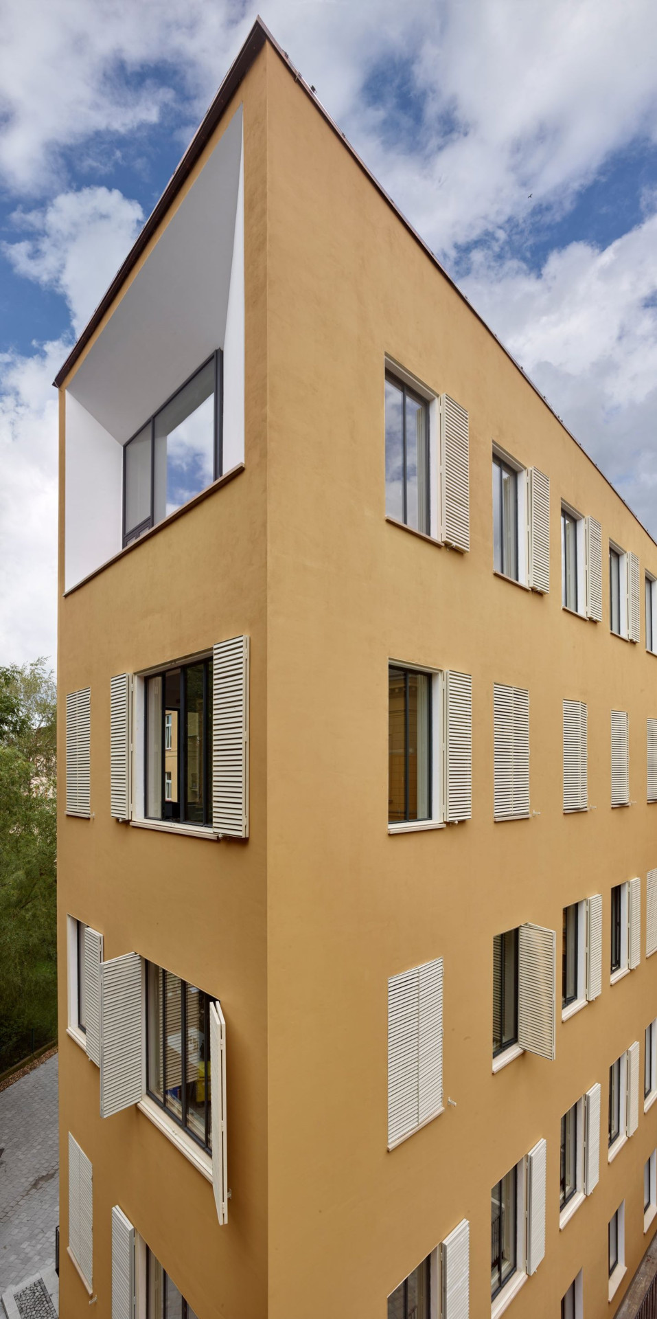 Racionálně pojatou fasádu s pravidelným rastrem oken obohacují okenice/stínidla nebo prosklení přes celou štítovou stěnu v posledním patře, za kterou se nachází zasedací místnost.