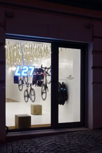 Cyklobutik L27, P6PA+Architects: Na prodejnu upozorňuje nejen bílý lesklý interiér, ale i neonový nápis umístěný do výlohy
