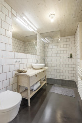 Koupelna je navržená minimalisticky. Dominuje tu bílá barva v kombinaci s dřevem. (Chata v Kořenově, Facha architekti)