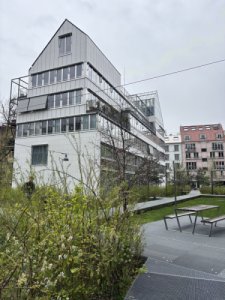 Budova je postavena z oceli, betonu a skla a má asymetrický tvar. (Komunitní bydlení v bývalé industriální zóně; Clauss Kahl Merz Atelier)