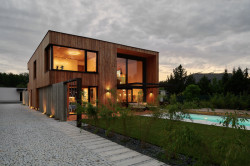 Dům je opláštěn dřevěným obkladem. Ten brzy zešedne, zeleň na zahradě vyroste a celý dům tak více splyne s okolím. (Dům ve třech zahradách, Air ateliér)