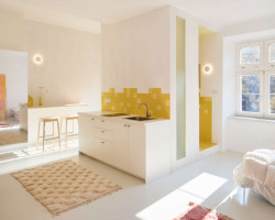 S barem sousedí drobná kuchyňská linka. (Byt pro malířku v Praze-Holešovicích od Plus One Architects)