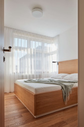 Ložnice navazuje na materiály zvolené pro obývací část - dubové dřevo v kombinaci se šedobéžovou. (Rekonstrukce bytu ve Strašnicích, MENU architekti)