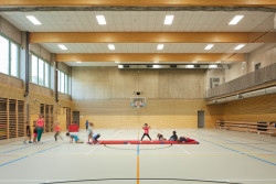 V tělocvičně dominují dřevěné prvky, pohledový beton a šedá podlaha s barevnými čárami pro různé sporty. (ZŠ bratří Fričů v Ondřejově; ATELIER 6)