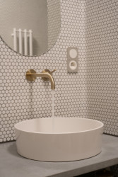 Bílý obklad doplňují mosazné baterie a niky s betonovými deskami. (rekonstrukce prvorepublikového bytu v Bubenči, Studio COSMO)