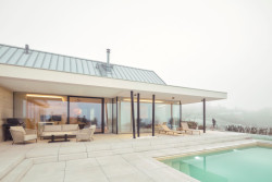 Černé subtilní rámy prosklených exteriérových stěn a černé sloupy dynamicky narušují jednolitost světlých ploch. (Bungalov ve východních Čechách; Atelier Kunc)