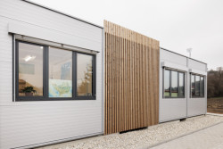 Moderní vzhled dodává stavbě použití elegantních šedých PUR panelů, velkých hliníkových oken a venkovních žaluzií. (ZŠ Drahanovice od společnosti KOMA)