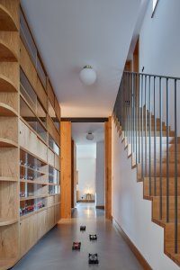 Interiéry vily v Klánovicích, KURZ architects: Tak autoři nazvali objekt, do kterého začlenili kuchyňskou linku, knihovnu i obývací stěnu, v jejímž středu visí televize.